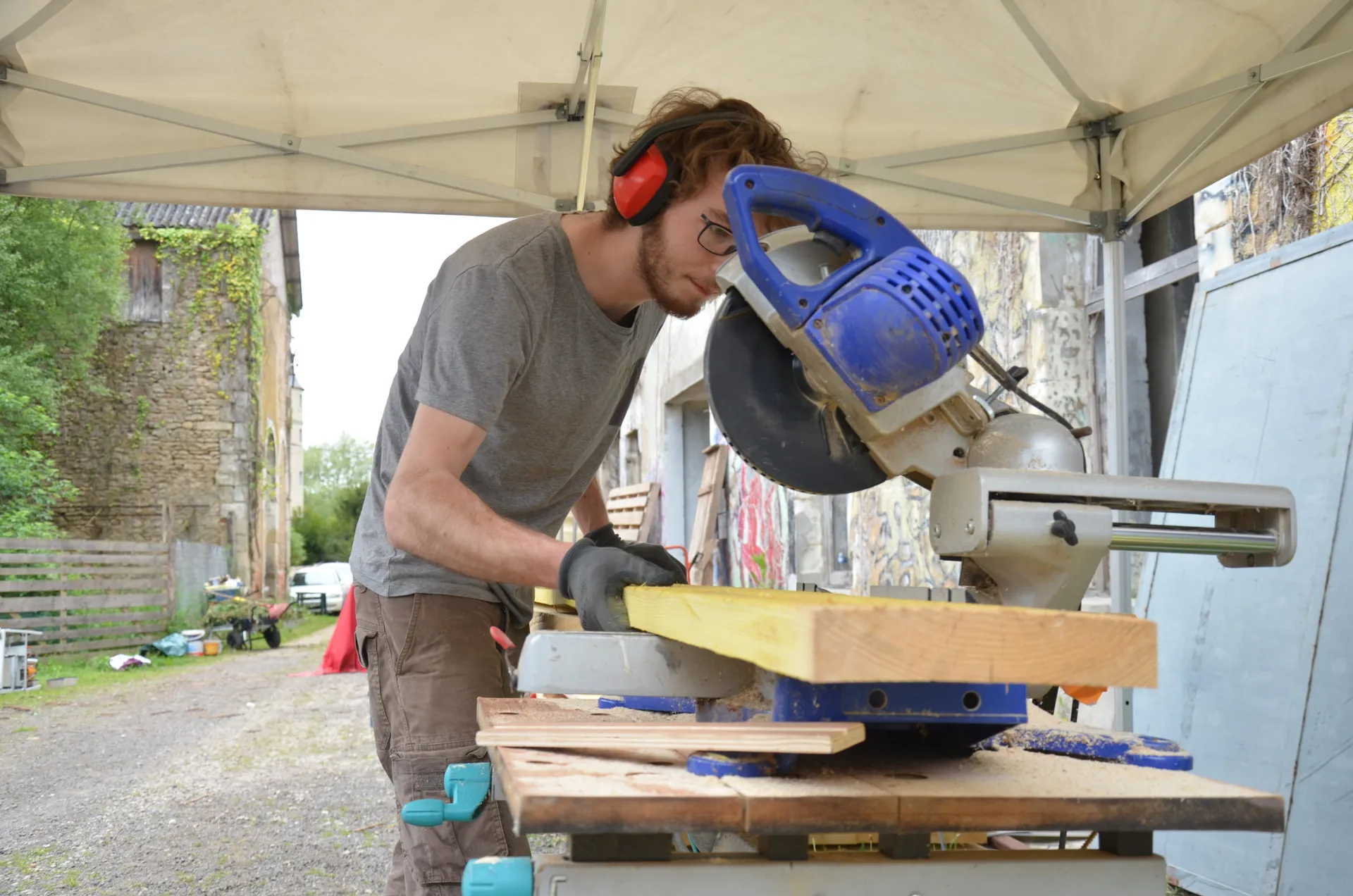 Découpe d’une pièce de bois à la scie, sur un chantier participatif des Usines